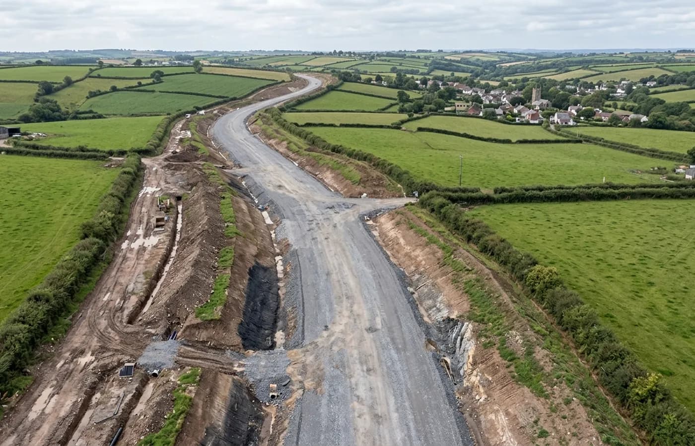 An aerial view along a road corridor under construction through Devon farmland, with the new carriageway formation running between hedgerows